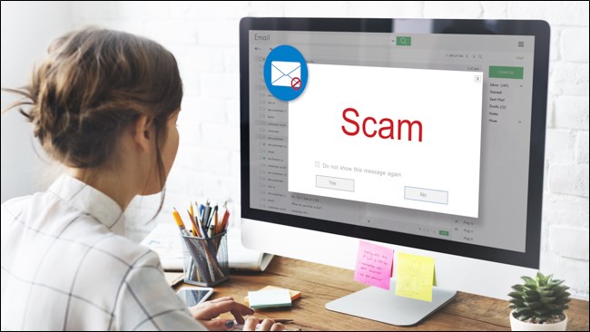 A woman opening an email on her computer that says "Scam."